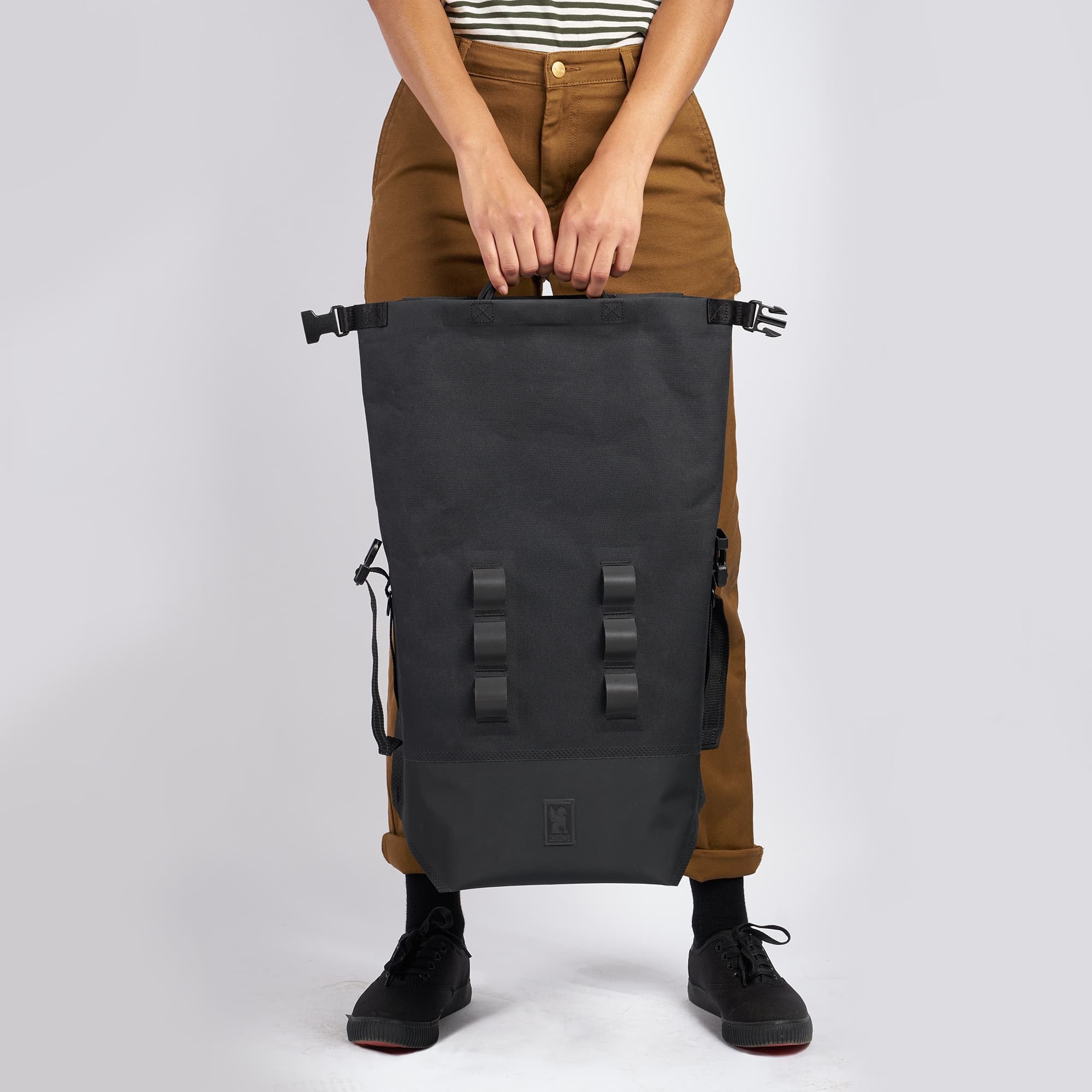 Waterproof 20L backpack in black top handles held by a woman  #color_black